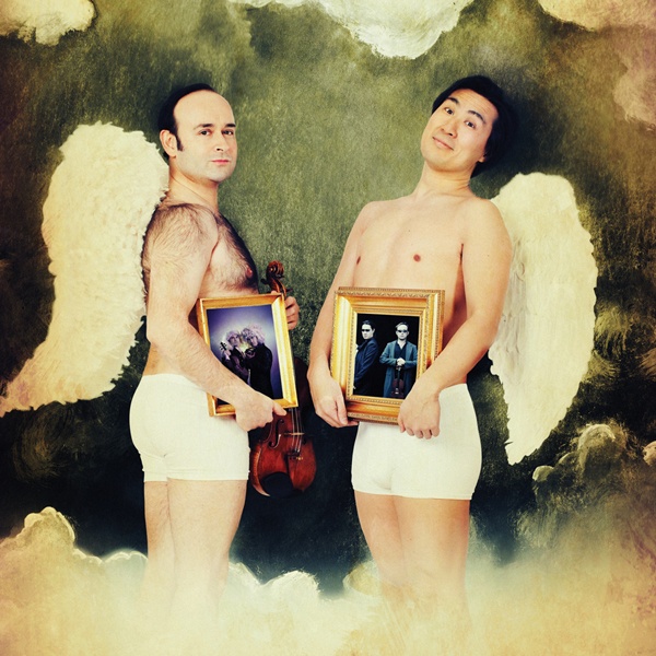 Igudesman dressed as angels holding framed photos.