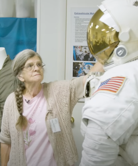 Photograph of seamstress Jo Thompson looking up at one of the Apollo spacesuits