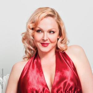 Storm Large in a red dress looking to the side.