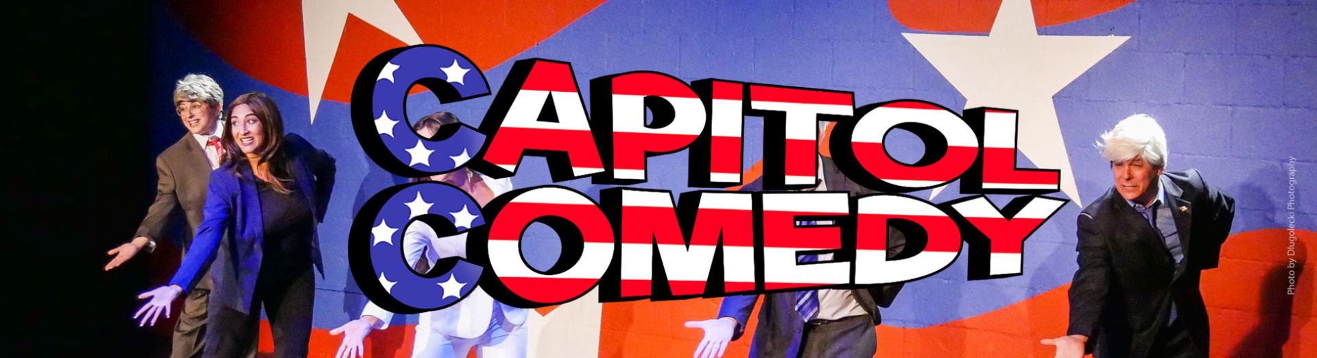 Members of the troupe on stage with the words Capitol Comedy in the center overlaid with the American flag.