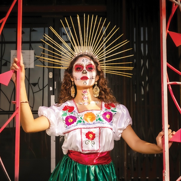A member of the dance troupe with elaborate face paint and costume for Dia de los Muertos.
