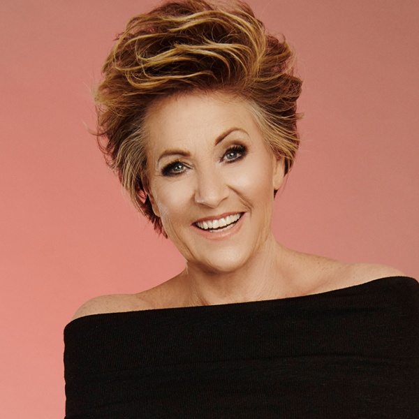 Lorna Luft in a black top against an orange background.