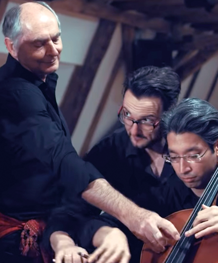 Three cellists all playing on the same instrument.