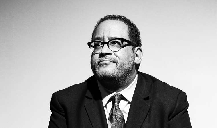 Michael Eric Dyson, in a suit and tie and glasses looking off to the side.