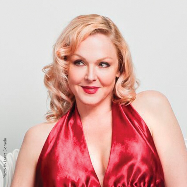 Storm Large in a red dress looking to the side.