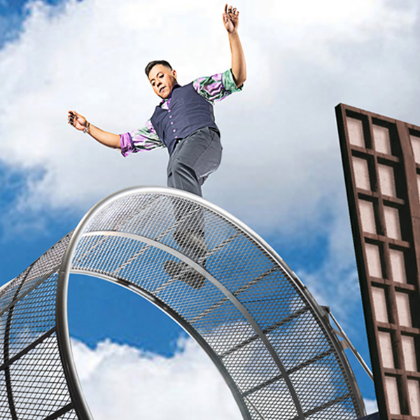 A member of Cirque Mechanics balancing atop a wheel.