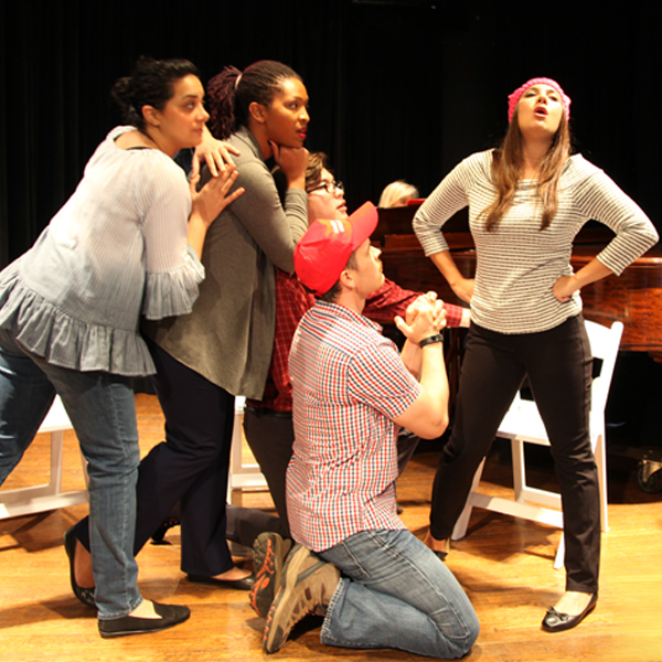 Five members of the troupe on stage performing a skit.