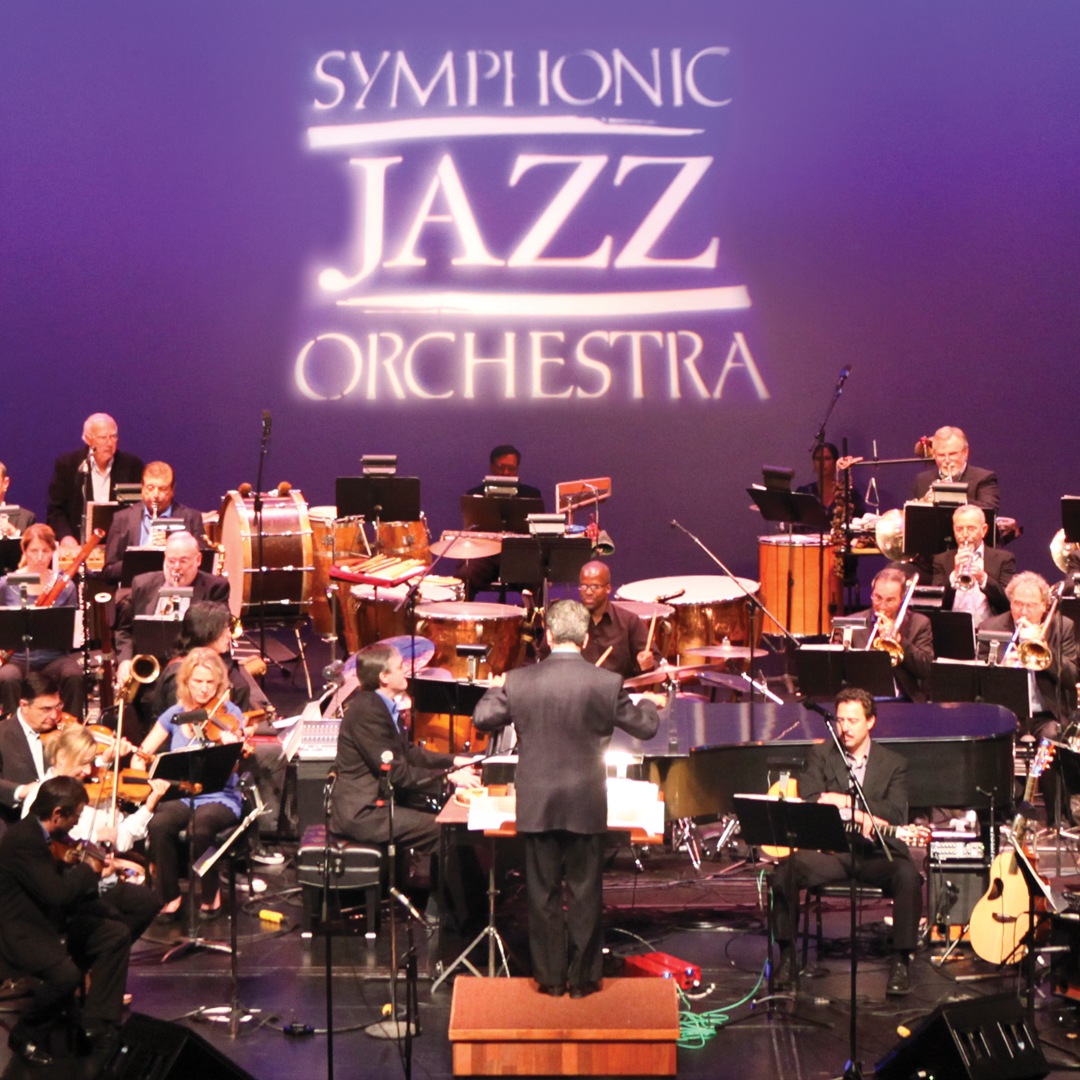 Members of Symphonic Jazz Orchestra on stage with their logo projected behind them. The logo reads Symphonic Jazz Orchestra.