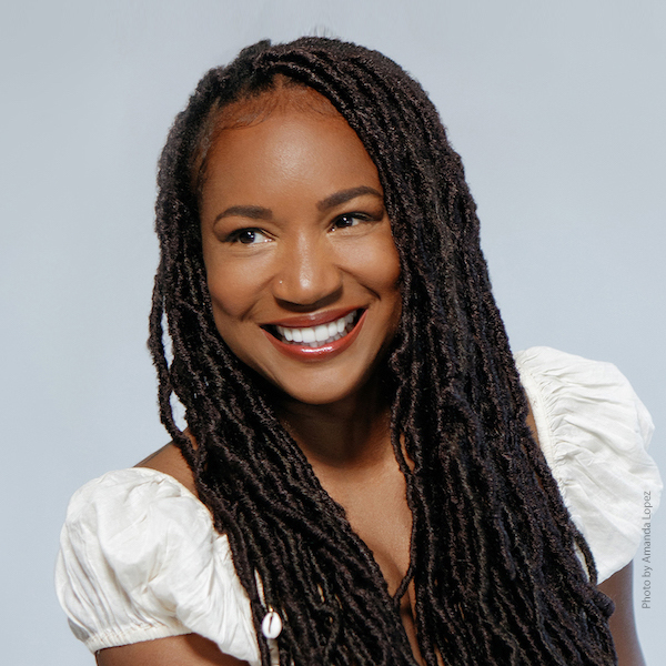 Miko Marks in a white top, smiling and looking to the side.