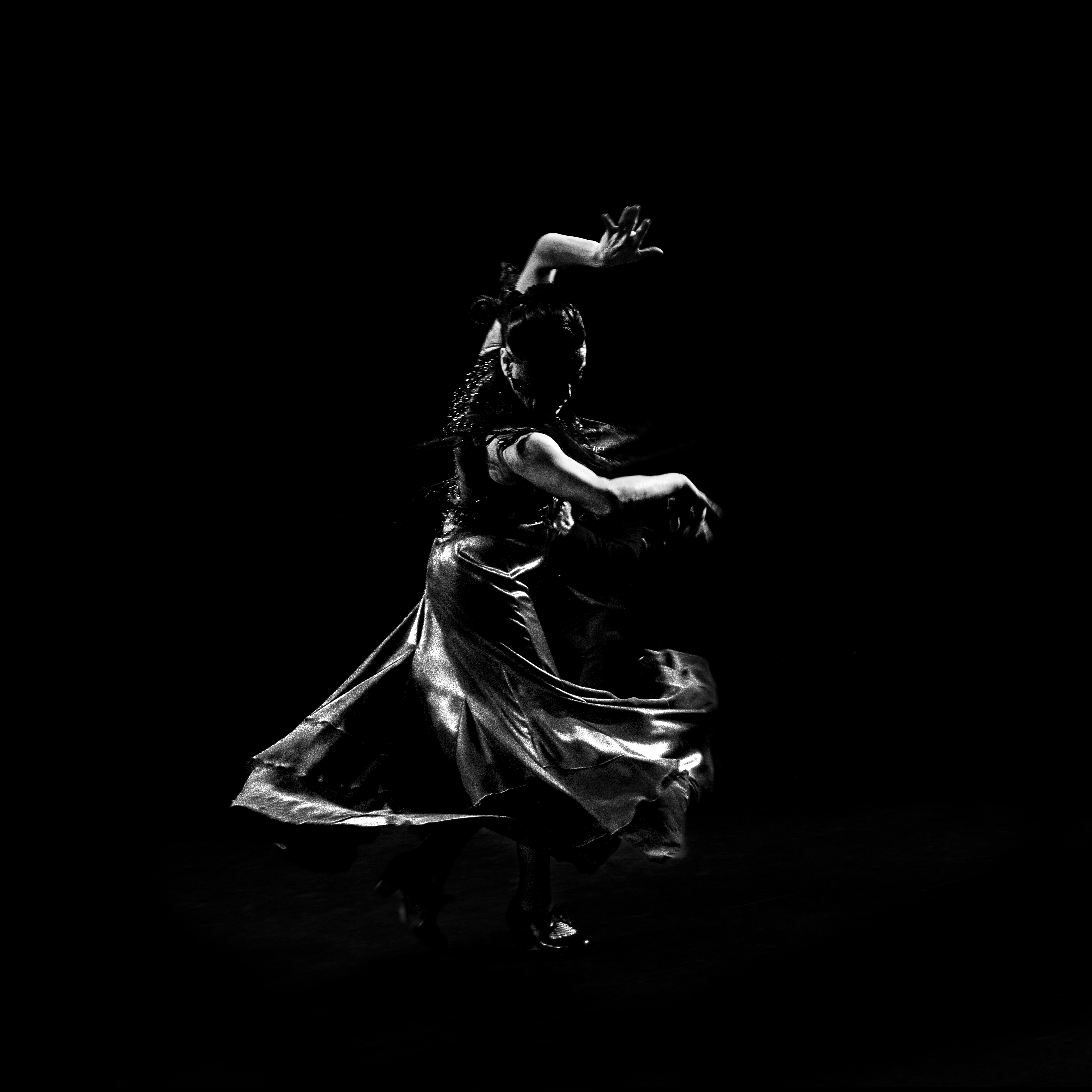 Flamenco dancer in motion with flowing dress on dark stage