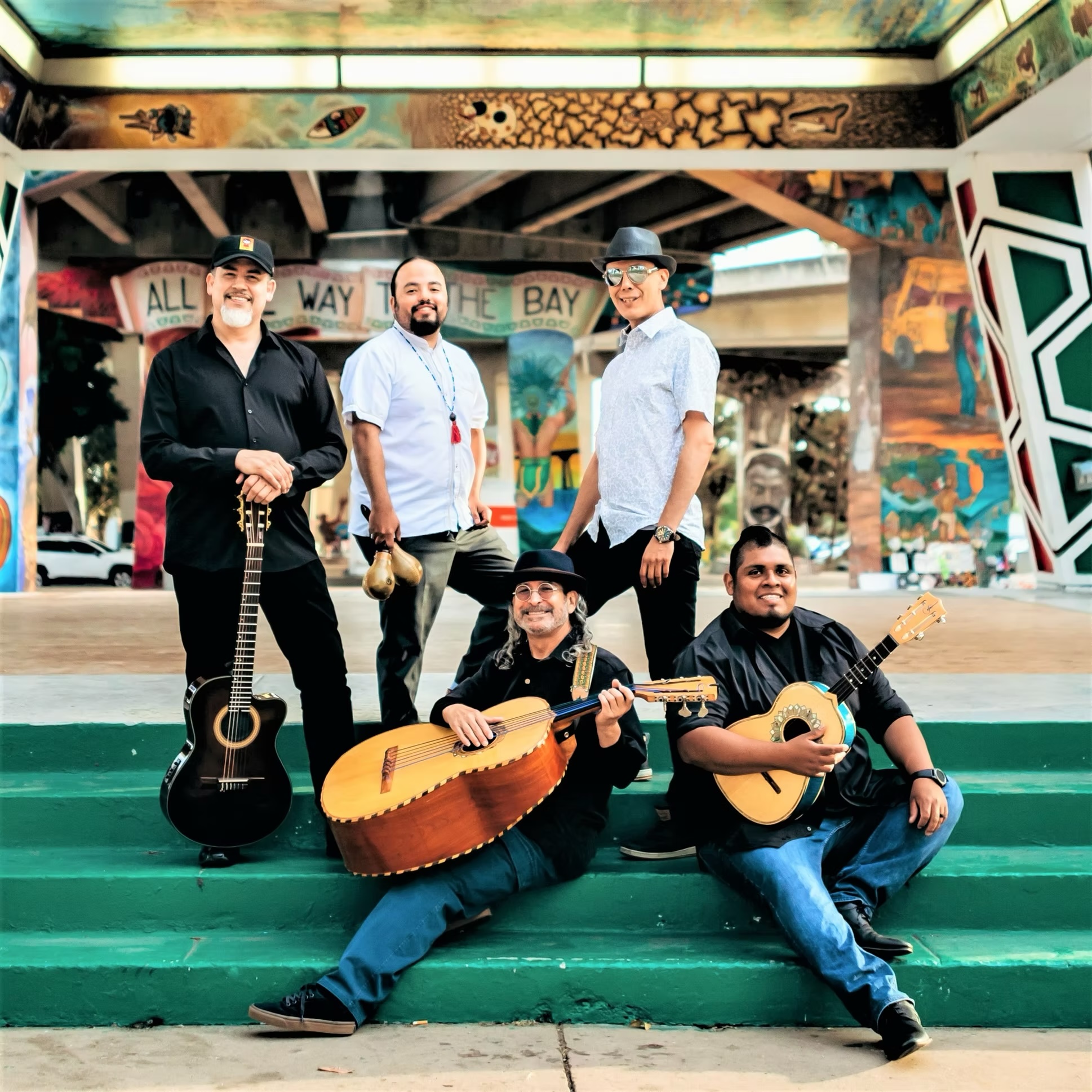 Members of Jarabe Mexicano with their instruments posing on a set of a stairs