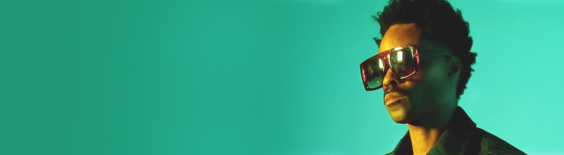 Bilal wearing sunglasses in front of a green background