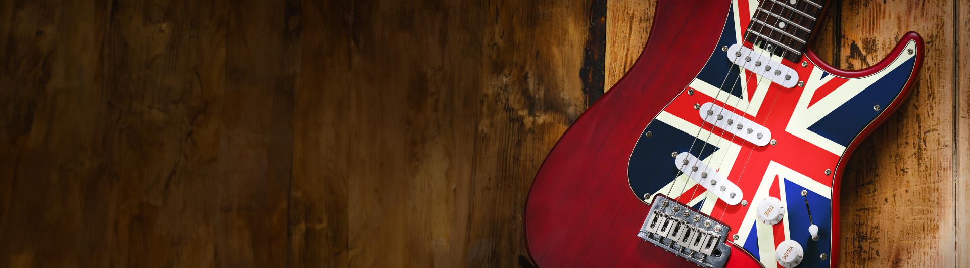 A guitar with the UK flag against a wood background