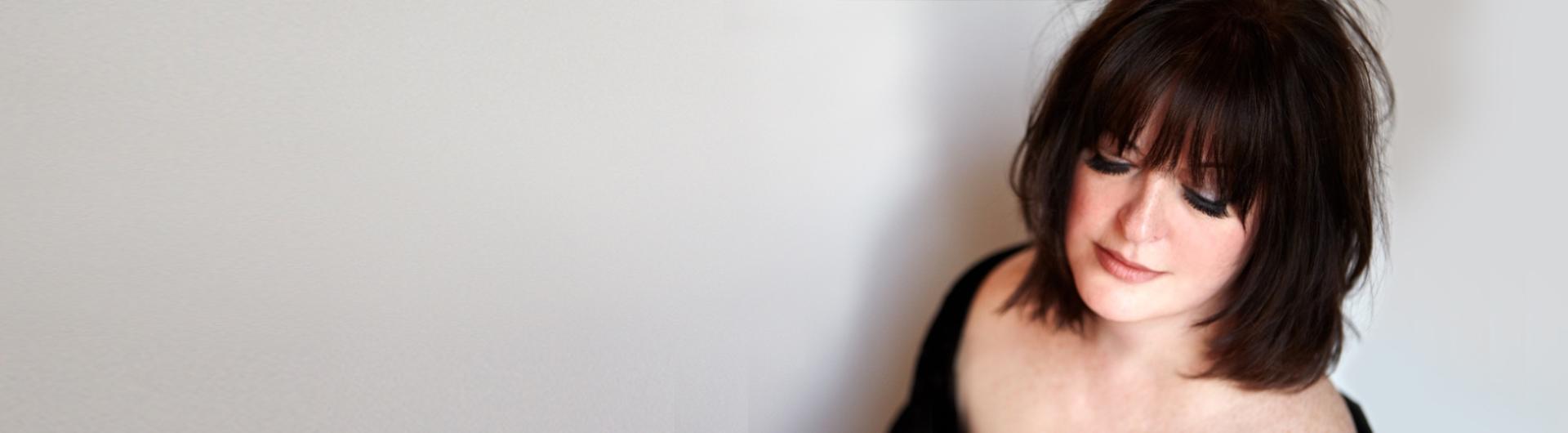 Ann Hampton Callaway looking down against a gray background.