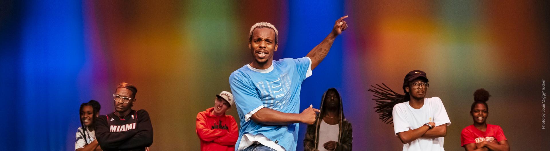Lil Buck and additional dancers against a colorfully lit background