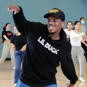 Lil Buck in a dark top that says Lil Buck leading a dance master class.