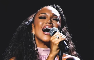 Chanté Moore holding a microphone and singing.