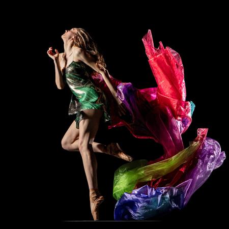 A dancer from Alonza King LINES Ballet in a green dress against a black background