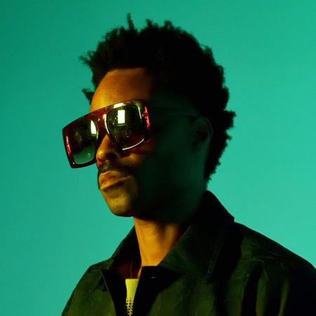 Bilal wearing large sunglasses against a green background