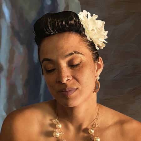 Kandace Springs wearing a large white flower in her hair and a necklace around her neck