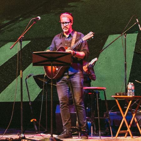 A member of Live From Laurel Canyon playing acoustic guitar on stage