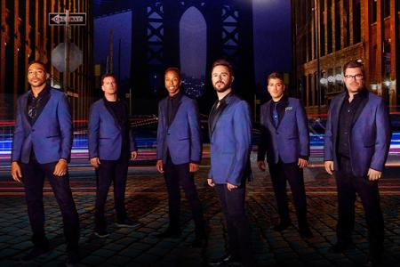 Members of the Doo Wop Project in blue blazers standing on a stage.
