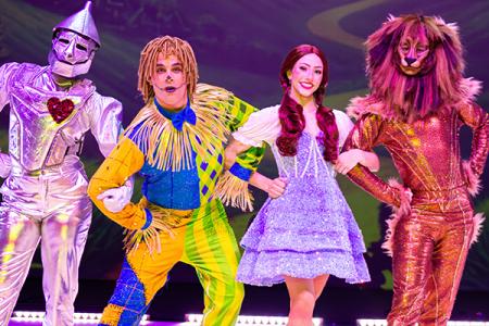 The tin man, scarecrow, Dorothy, and the lion from Wizard of Oz in costume on stage.