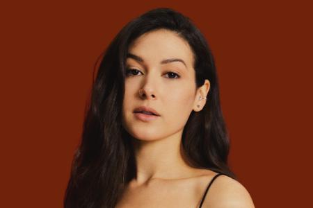 Nella with long black hair against a red background.