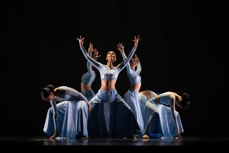 Sa Dance Company performers in flowing pale-blue costumes pose dramatically on a dark stage.