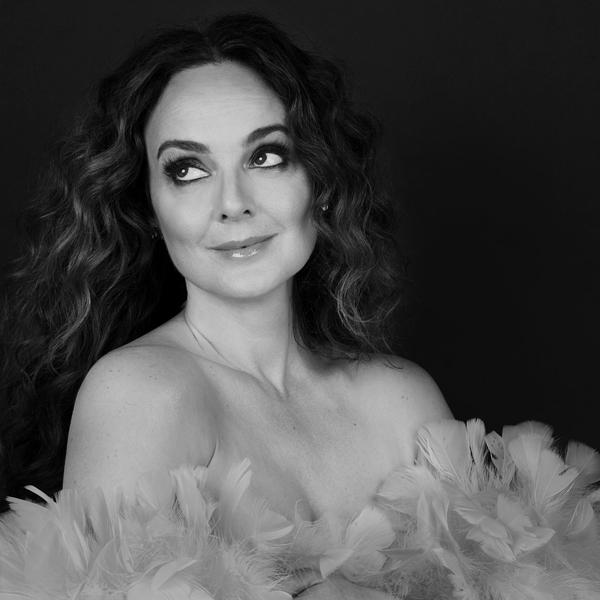 Melissa Errico with a smile, gazing to the side.