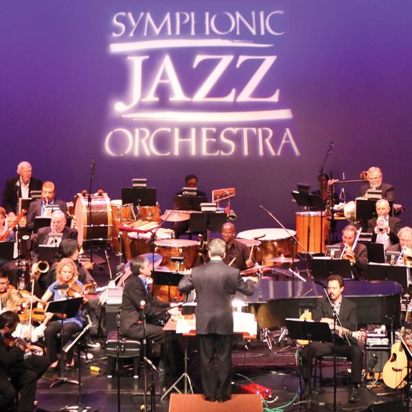 Members of the Symphonic Jazz Orchestra on stage with their logo projected behind them.