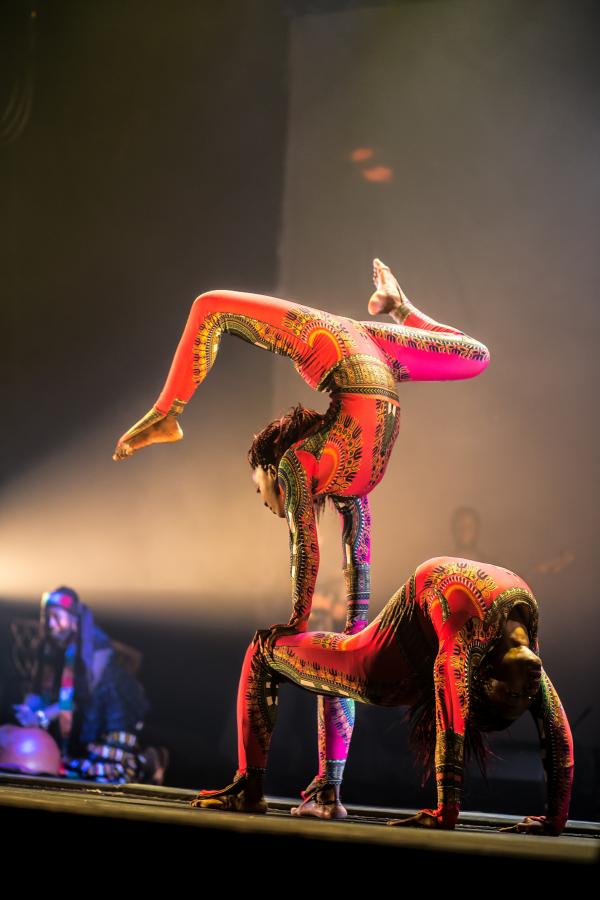 Two contortionists on stage, on balancing on the knees of another